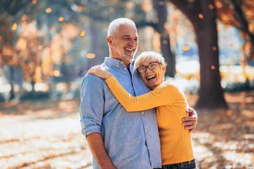 older couple hugging outside | implant dentures bellevue