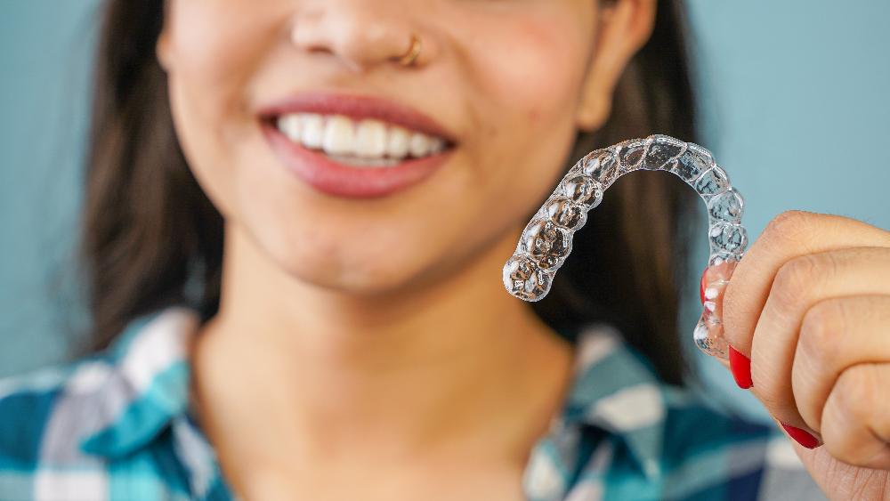 patient holding clear plastic aligner | clear aligners bellevue tn